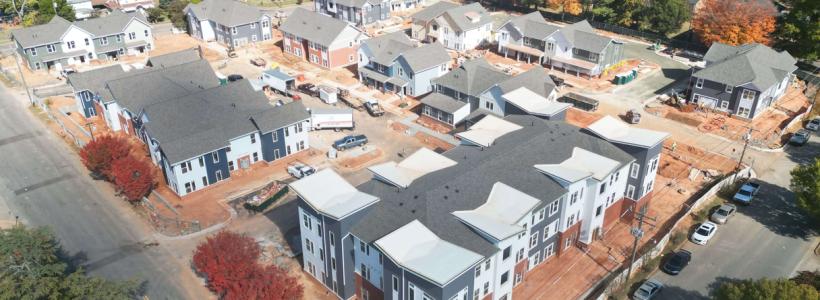 Aerial photo of gray and white, three and four-story apartment buildings.